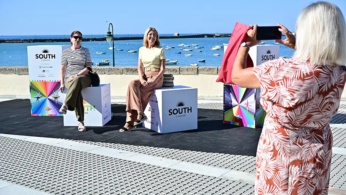 Unas amigas se sientan el Photocall mientras otra persona le toma una foto.
