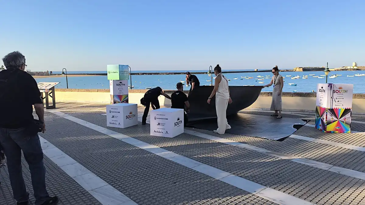 Los trabajadores levantan un plástico transparente que cubría la alfombra roja instalada frente al mar.
