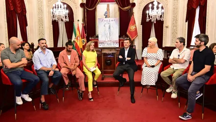Imagen del Salón de Plenos del Ayuntamiento de Cádiz con el alcalde Bruno García y la concejala Maite González, posando con varios artistas que participarán en Cádiz Romana 2025.