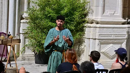 Una persona vestido a la usanza romana muestra prácticas médicas antiguas con hierbas y utensilios, durante una escenificación en el patio de la Casa del Obispo