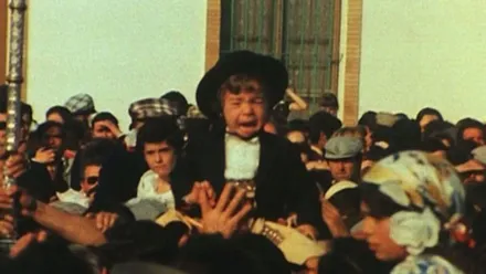 Niño vestido de corto siendo acercado, en brazos de la multitud, a la Virgen del Rocio.