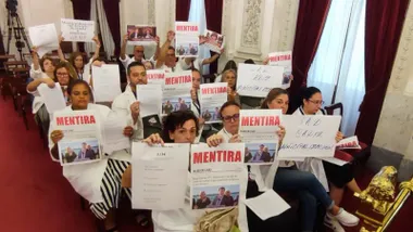 Varias trabajadoras de Ayuda a Domicilio sentadas entre el público en el Pleno municipal de Cádiz, sostienen carteles blancos con la palabra ‘mentira’ escrita en grande y en mayúsculas.