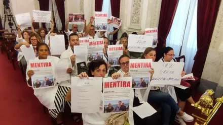Varias trabajadoras de Ayuda a Domicilio sentadas entre el público en el Pleno municipal de Cádiz, sostienen carteles blancos con la palabra ‘mentira’ escrita en grande y en mayúsculas.