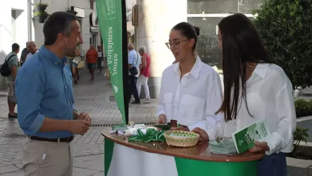 Vera junto a dos chicas de blanco y verde en el stand de movilidad.
