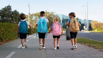 Niños y niñas con mochilas camino de la escuela.