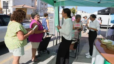Chicas informando a la ciudadanía sobre movilidad, bajo una carpa verde.