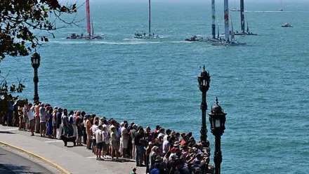 Numeroso público observa las regatas de la SailGP desde el Paseo de Santa Bárbara en Cádiz, con las murallas y el mar al fondo.