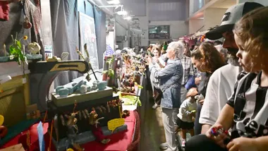 Varias personas, entre ellas familias con niños, observan los puestos decorados de Tosantos en el interior de un mercado de Cádiz.