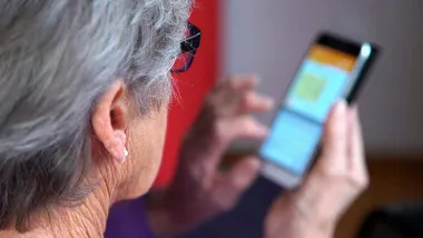 Mujer, con canas, manejando un teléfono móvil.