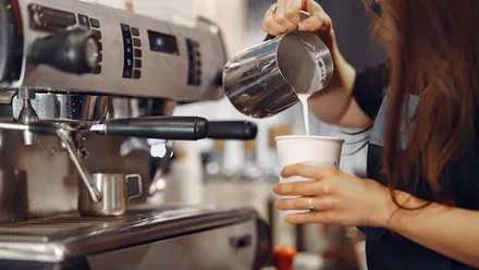 Chica manipulando una cafetera.