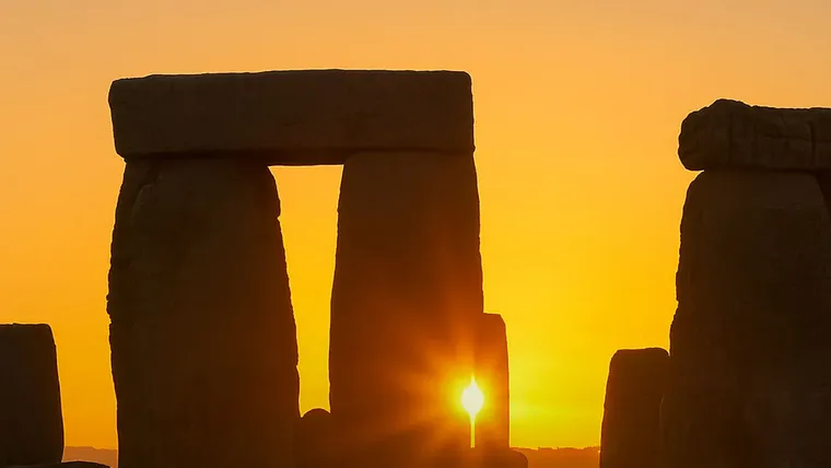 Monumento megalítico y el sol emergiendo entre los arcos.
