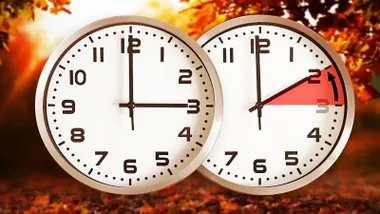 Dos relojes, uno marca las 3 y otro las 2. Fondo otoñal.