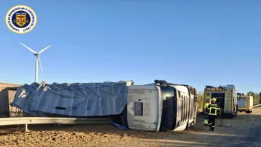 Camión volcado en la carretera y bomberos asistiendo al conductor.
