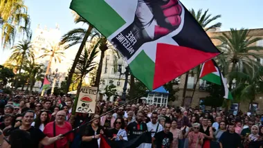 Multitud de personas en la Plaza de San Juan de Dios de Cádiz con una gran bandera de Free Palestine ondeada por una mujer.