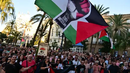 Multitud de personas en la Plaza de San Juan de Dios de Cádiz con una gran bandera de Free Palestine ondeada por una mujer.