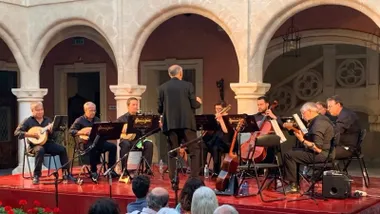 Músicos tocando una pieza en el escenario roteño. Visten de negro sobre suelo rojo.