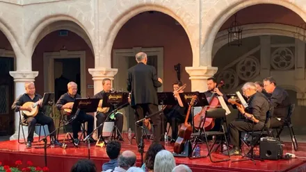 Músicos tocando una pieza en el escenario roteño. Visten de negro sobre suelo rojo.
