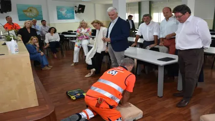 Sanitario en el suelo practicando una RCP al un muñeco ante la mirada de otras personas.