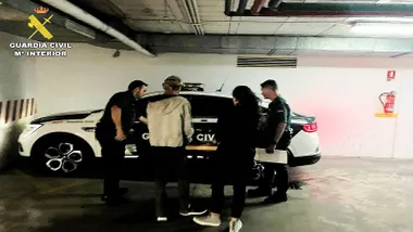 Agente de la Guardia Civil introducen en un vehículo a los dos detenidos.