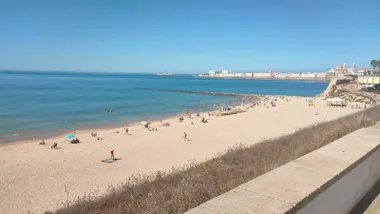 Imagen de la playa de Santa María del Mar de Cádiz co nel casco antiguo y la catedral de fondo.