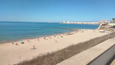 Imagen de la playa de Santa María del Mar de Cádiz co nel casco antiguo y la catedral de fondo.
