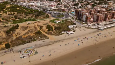 Vista desde el aire de la playa de Matalascañas con el mural de residuos y voluntarios trabajando