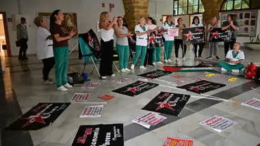 Fotografía de un grupo de trabajadoras del servicio de limpieza de la Universidad de Cádiz concentradas frente a la Facultad de Filosofía. Varias mujeres, con chalecos y camisetas de trabajo, levantan pancartas y megáfonos mientras corean consignas como “Sin un buen pliego, no te friego” y “Si quieres brillo, arráscate el bolsillo”. El ambiente es reivindicativo y sereno, con gestos de determinación y compañerismo.