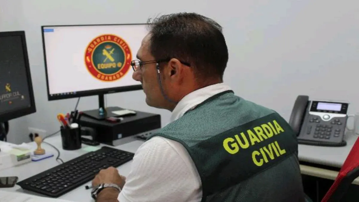 Agente de la Guardia Civil controlando un ordenador con fondo del escudo de la unidad.
