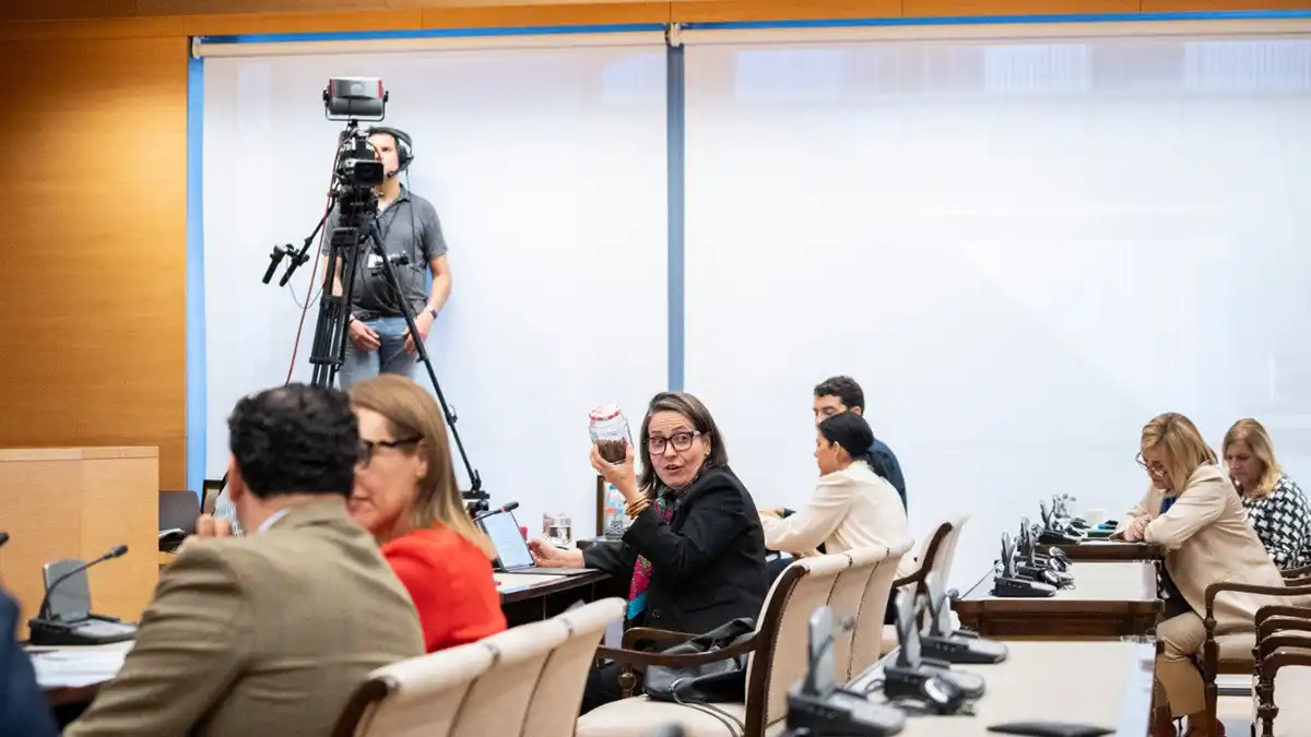 Esther Gil de Reboleño, diputada por Cádiz de SUMAR, sostiene un frasco con alga asiática Rugulopterix okamurae mientras interviene ante la Comisión de Industria y Turismo del Congreso de los Diputados. Explica su propuesta para transformar el impacto del alga invasora en una fuente de empleo e innovación sostenible en la costa gaditana.