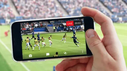 Mano sosteniendo un móvil en el que se ve el fútbol.