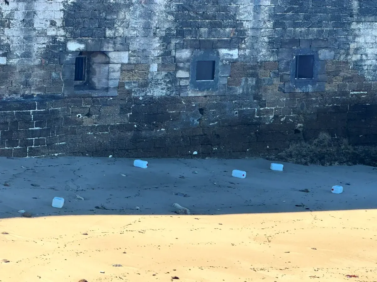 Garrafas tiradas en la arena y la uralla de la playa junto a la Baterñía de San Felipe.