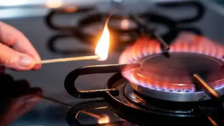 Mano con un cerillo encendiendo una hornilla de gas.
