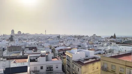 Vista panorámica de Cádiz con la catedral, el pirulí y varios edificios del casco histórico con un cielo blanquecino típico de los días de bochorno.