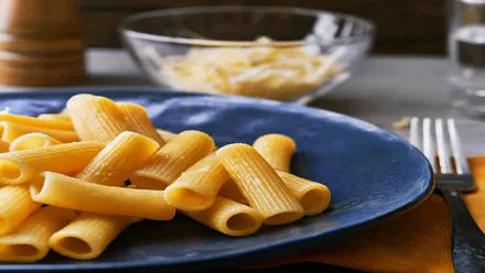 Plato azul con macarrones y un cubierto al lado.