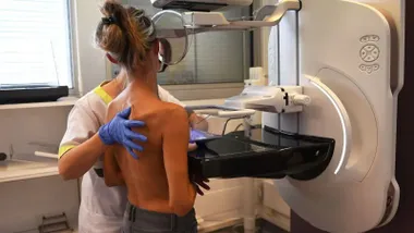 Mujer y una técnico sanitaria realizando una mamografía.