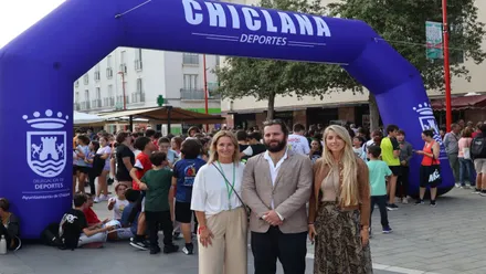 Los delegados del ayuntamiento de Chiclana posan delante de la meta de la marcha en color azul y letras blancas.
