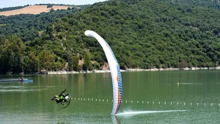Piloto de un paramotor realizando una pirueta rozando el lago.