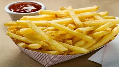 Recipiente con patatas fritas y un bol de tomate, de ketchup.