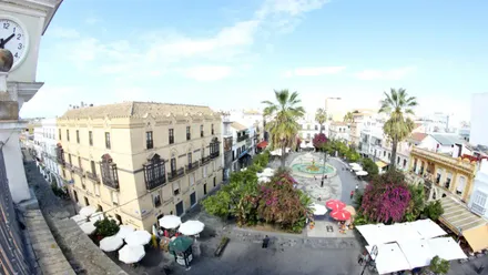 Fotografía de la Plaza del Cabildo de Sanlúcar de Barrameda captada desde el Antiguo Ayuntamiento, donde se distingue la fuente central, las palmeras y las terrazas de los bares .