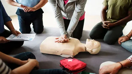 Chica practica una RCP a un dummie de entrenamiento.
