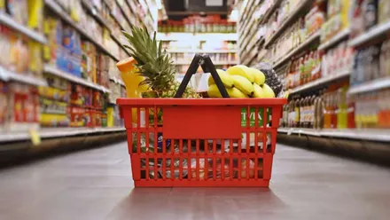 Cesta de la compra en rojo con productos de un supermercado.