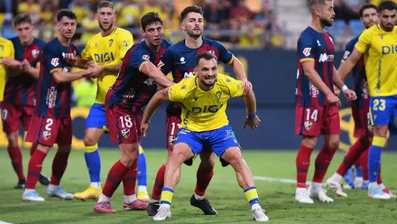Tabatadze puja por la posición con un defensa de la SD Huesca en un saque de esquina con varios jugadores más de ambos equipos detrás.