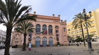 Fachada del Gran Teatro Falla en una jornada en la que han aparecido más nubes en los cielos de Cádiz, algunas de las cuales se aprecian en la imagen.