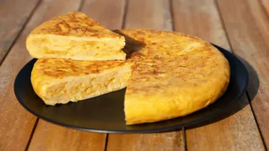 Jugosa tortilla de patatas en un plato negro.