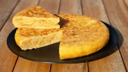 Jugosa tortilla de patatas en un plato negro.