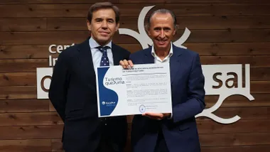 Óscar Perelli y José María Román en el acto, sostiene el título de "Turismo que suma".