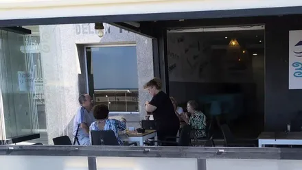 Una camarera sirve bebidas en una terraza del Paseo Marítimo de Cádiz.