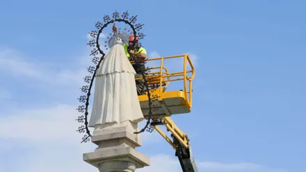 Operario colocando elementos en la estatua de la Virgen del Rosario en la rotonda de Rota.