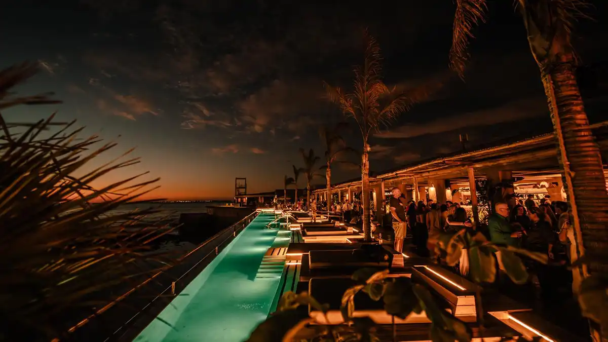 La piscina infinita de Calachica con el cielo aún reflejando los colores del atardecer en la Bahía de Cádiz.