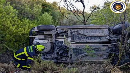 Bombero junto al automóvil volcado.
